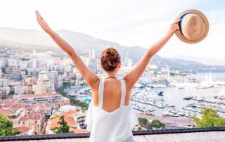 Woman looking out over a city with her hands stretched out in the air